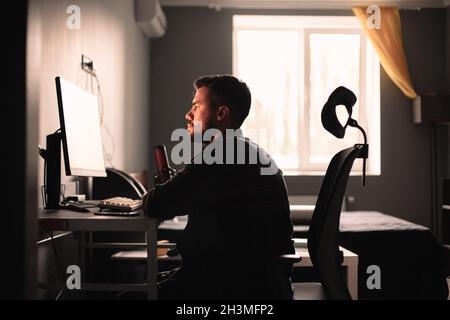 Mann, der zu Hause am Schreibtisch sitzt und am Computer arbeitet Stockfoto