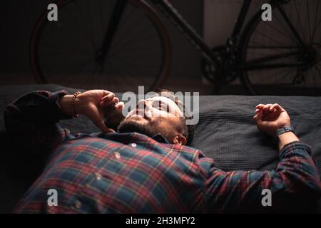 Glücklicher Mann, der auf dem Smartphone spricht und zu Hause auf dem Bett liegt Stockfoto