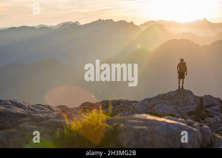 Backpacker steht auf einem Felsvorsprung und blickt auf die Aussicht. Stockfoto