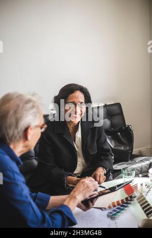 Lächelnde Kollegen und Kolleginnen diskutieren im Workshop Stockfoto