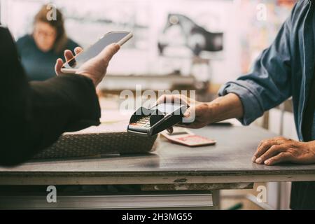 Kurze Hand einer Kundin, die kontaktlos im Einzelhandel bezahlt Stockfoto