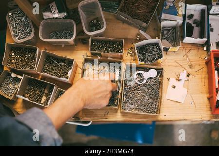 Direkt über dem Schuss des Mannes mit Nagel - Arbeitswerkzeug über dem Tisch im Laden Stockfoto