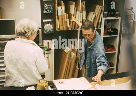 Männlicher Unternehmer untersucht Rahmen mit einer Kollegin in einem Frame-Workshop Stockfoto