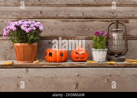 halloween Kürbisse, Blumen mit alter Laterne auf Holztreppe. Gartendekoration mit Herbstblättern Stockfoto