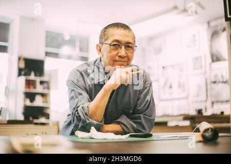 Leitender Handwerker mit Hand am Kinn in der Werkstatt Stockfoto