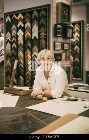 Porträt einer Unternehmerin, die sich in der Werkstatt über den Tisch lehnt Stockfoto