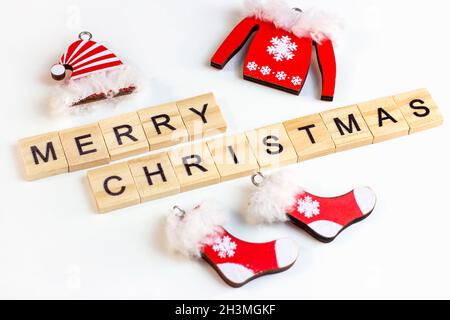 Leuchtend rote Weihnachten Weihnachtsmann Kleidung auf weißem Hintergrund mit hölzernen Frohe Weihnachten Text. Traditionelles Konzept für die Feier der Winterferien. Stockfoto