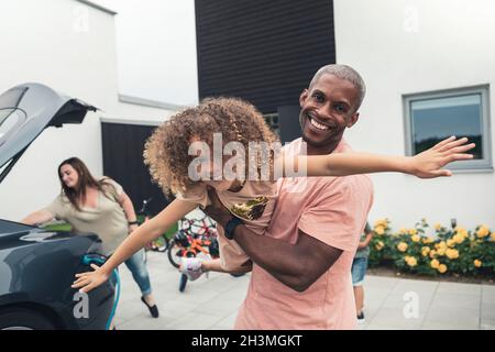 Porträt eines lächelnden Mannes, der mit seiner Tochter im Vorgarten spielt Stockfoto