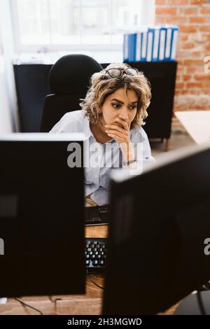 Eine professionelle Frau, die am Schreibtisch im Büro am Computer sitzt Stockfoto