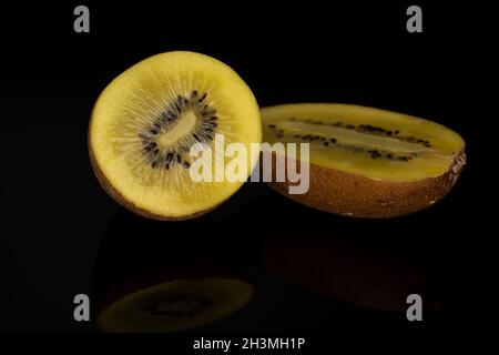 Zwei Hälften reifer Bio-süßer, köstlicher goldener Kiwi auf schwarzem Hintergrund. Stockfoto