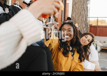 Lächelnde Freundinnen, die während der Party einen Drink zu sich nehmen Stockfoto