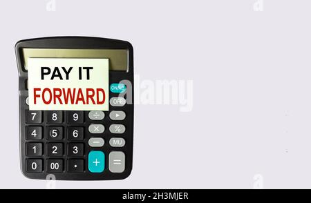 Die Phrase Pay IT Forward auf einem Aufkleber auf einem Rechner und einem weißen Hintergrund. Stockfoto