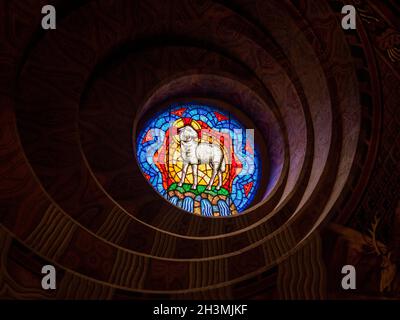 Glaslamm über dem Eingang der Mathias-Kirche: Ein wunderschönes Glasfenster, eingerahmt von asymmetrischen Ovalen, das ein Lamm über dem Eingang der Mathias-Kirche in Buda darstellt. Stockfoto