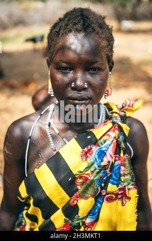 BOYA STAMM, SÜDSUDAN - 10. MÄRZ 2020: Frau in traditionellen bunten Kleidern und Accessoires mit rituellen Piercing und Narbe Mo Stockfoto