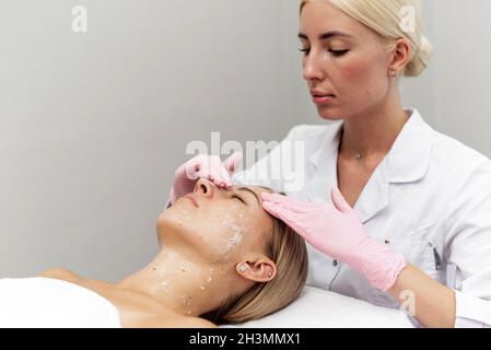 Die Kosmetikerin reinigt und befeuchtet die Haut des Patienten im Spa-Salon. Stockfoto