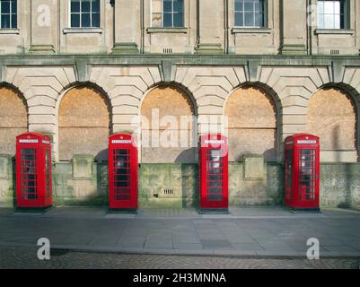 Eine Reihe von vier traditionellen britischen roten Telefonzellen vor einem alten verlassenen Postgebäude in blackpool, england Stockfoto