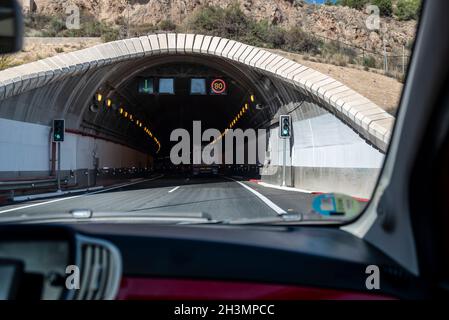 Fahrt in den Tunnel de Lorca, A-7 Straßentunnel in Lorca, Region Murcia, Spanien. Innenansicht des Tunneleingangs mit Lastwagen, Geschwindigkeitsbegrenzung Stockfoto