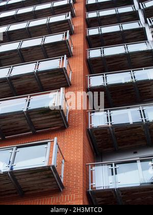 Blick auf ein modernes Apartmentgebäude mit Fenstern in Ziegelwänden und Glasbalkonen Stockfoto