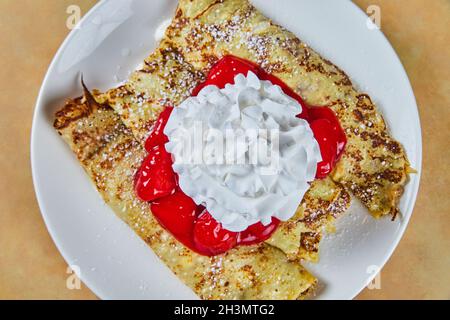 Klassische Crepes mit Erdbeermischung und Schlagsahne Stockfoto
