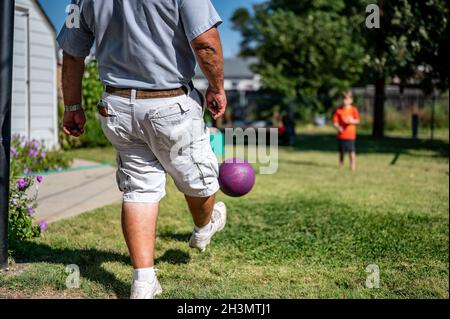 Kickball mit Großvater im Hinterhof spielen Stockfoto