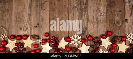 Weihnachtsbanner mit Holzstern und roten Kugeln. Blick von oben auf einem alten Holzhintergrund. Stockfoto