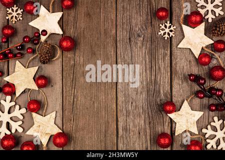 Weihnachtliche Doppelbordüre mit Holzstern-Ornamenten und roten Kugeln. Blick von oben auf einem rustikalen Holzhintergrund. Stockfoto