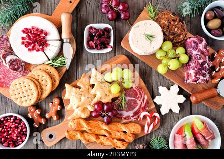 Weihnachtliche Tischszene mit Charcuterie vor dunklem Holzhintergrund. Auswahl an Käse- und Fleischgerichten. Draufsicht. Stockfoto