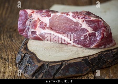 Rohe Schweineschulter auf dunklem Holz Stockfoto