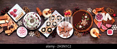 Verschiedene Weihnachtsdesserts und Süßigkeiten. Panorama-Tischszene von oben auf einem rustikalen Holzhintergrund. Bundt-Kuchen, Schokoladenkuchen, Hacktektar Stockfoto