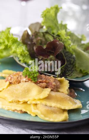 Ravioli mit Sahnesauce und Salat Stockfoto