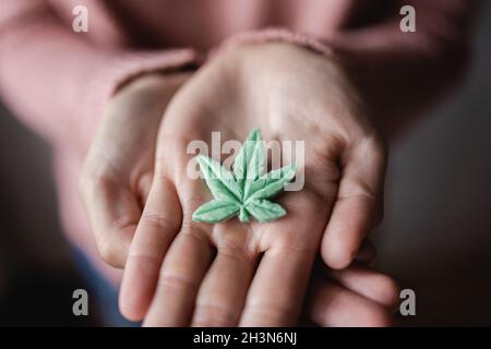 CBD-Süßigkeiten - Hände mit essbarem Cannabisblatt zur Angstbehandlung - Marihuana alternative Medizin Stockfoto