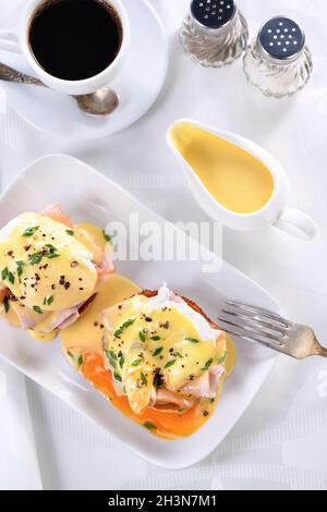 Hollandaise Buttersauce in einem Soße Boot zum Frühstück mit Eiern Benedict serviert - gebratenes englisches Brötchen, Stockfoto