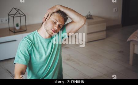 Mann dehnt seine Nackenmuskeln. Workout am Morgen. Gesundheitswesen Stockfoto