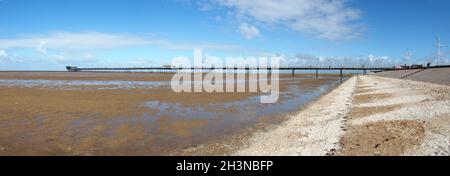 Lange Panoramaaussicht auf den southport Pier vom Strand mit blauem Scheu, der sich bei Ebbe im Wasser am Strand spiegelt Stockfoto