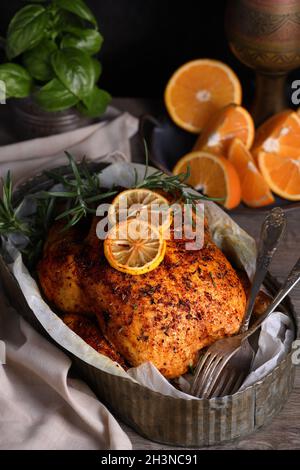 Gebackenes Hähnchen in Gewürzen mit knusprig appetitlich gebratener Kruste in einem Tablett, dunkel launisch Stockfoto