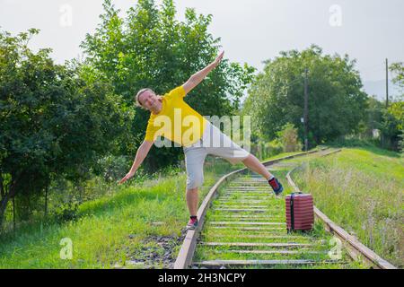 Brunette Reisende mit einem Koffer auf den Schienen geht Stockfoto