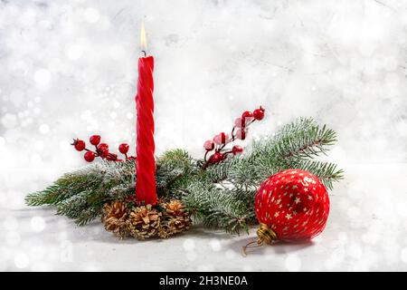 Brennende rote Kerze mit schneebedeckten Tannenzweigen. Weihnachtsadvent. Stockfoto