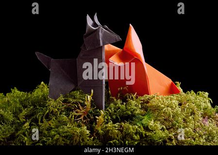 Origami Papier Wolf und Fuchs auf grünen Moos Insel isoliert auf schwarzem Hintergrund Stockfoto