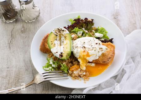 Ein gesunder und ausgewogener Frühstücksteller. Benedict's Ei breitet sich auf einem gerösteten Toast mit einem halben avoca aus Stockfoto