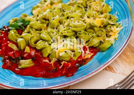 Grüne Tortellini mit gebackenem roten Paprika in Tomatensauce Stockfoto