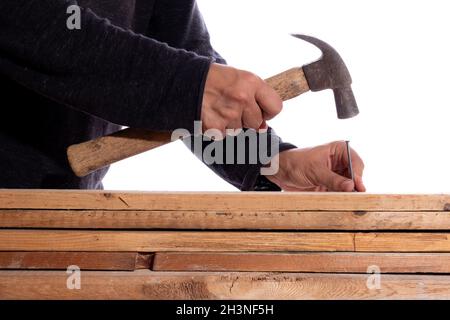 Mann, der Nägel in Holz eingeschlagen hat, isoliert auf weißem Hintergrund. Unbekannter Mann in der Zimmerei. Stockfoto