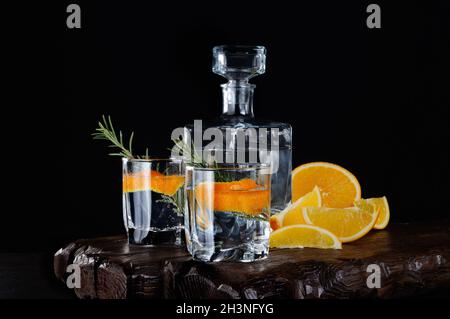 Cocktail klassischer Dry Gin mit Tonic und Orangenschale Ein Zweig Rosmarin auf einem Holzbrett mit Stockfoto