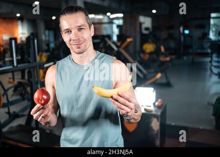 Junge gutaussehende Sportler hungrig und essen gesunde Apfelfrüchte im Fitnessstudio Stockfoto