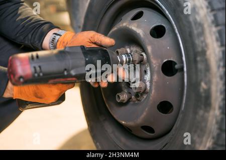 Kfz-Mechaniker Arbeiter tun Reifen oder Rad Austausch mit Elektroschrauber in der Garage der Reparatur-Service-Station Stockfoto