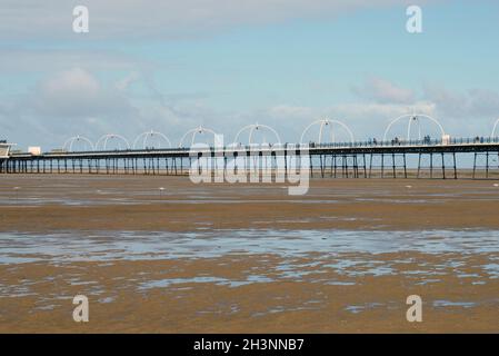 Panoramablick auf den southport Pier vom Strand mit blauem Scheu, der sich bei Ebbe im Wasser am Strand widerspiegelt Stockfoto