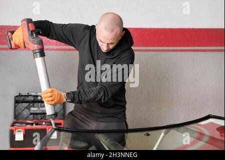 Glaser auftragen der Gummidichtung auf die Windschutzscheibe in der Garage, Nahaufnahme. Stockfoto