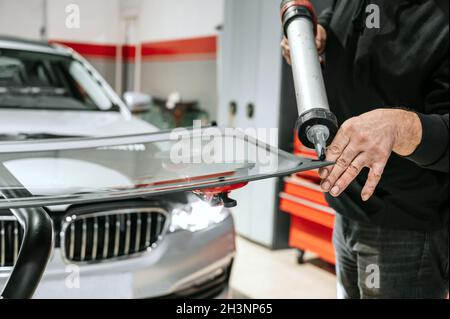 Glaser auftragen der Gummidichtung auf die Windschutzscheibe in der Garage, Nahaufnahme. Stockfoto