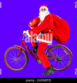 Fröhlicher Weihnachtsmann in einem Neujahrshut und roter Kleidung fährt mit einer Geschenktüte auf dem Fahrrad. Drei Isolate auf weißem Hintergrund. Frohes neues ja Stockfoto