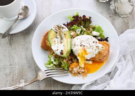 Ein gesunder und ausgewogener Frühstücksteller. Benedict's Ei breitet sich auf einem gerösteten Toast mit einem halben avoca aus Stockfoto