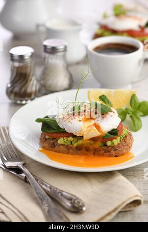 Frühstück. Beste Eier Benedikt auf einer Scheibe geröstetes Getreidebrot mit Guacamole und Spinat Stockfoto